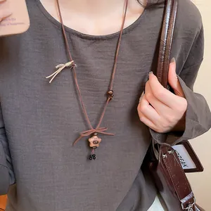 Close-up of vintage wooden bear and star pendant necklace on a long brown cord