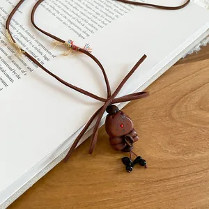 Close-up detail of a vintage wooden bear pendant necklace on an open book surface