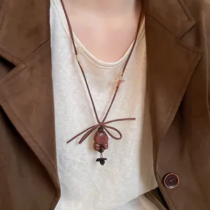 Detail shot of vintage wooden bear pendant necklace with bow on brown suede jacket