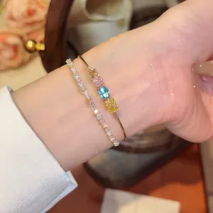 Detail shot of an 18k gold plated bangle with colorful cubic zirconia stones on a wrist.