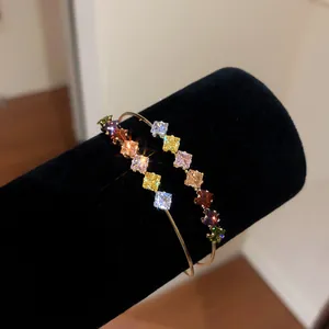 Close-up of 18k gold plated open bangle with sparkling multi-colored square zirconia stones