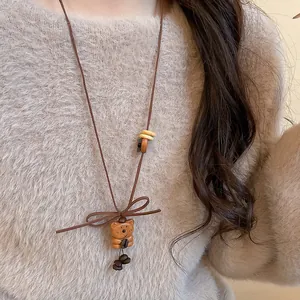Close-up of a vintage wooden bear pendant sweater necklace with brown cord and bow detail
