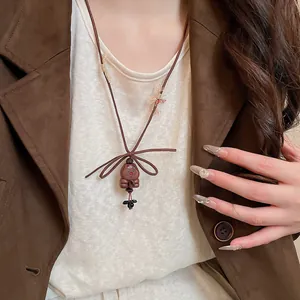 Close-up of a retro wooden bear pendant necklace worn by a model with a brown blazer.