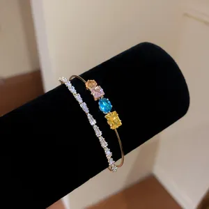 Detail of 18k gold plated bangle with colorful gemstones and clear zircon tennis bracelet.