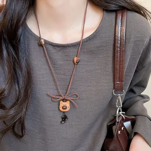 Close-up of a cute wooden bear charm necklace on a brown cord with a bow detail.