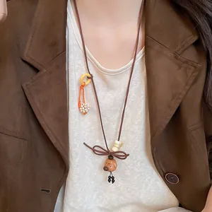 Detail of vintage wooden bear pendant necklace with bow and tassel accents.