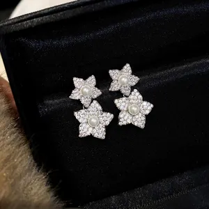 Close-up of elegant flower stud earrings with micro-pave zircons and pearls in a black gift box
