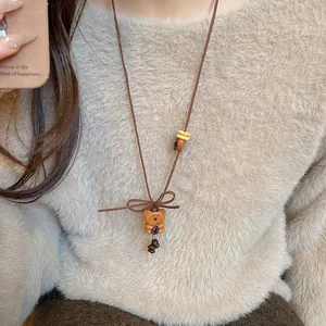 Detailed view of a cute wooden bear pendant necklace styled on a cozy beige sweater