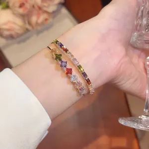 Close-up of elegant gold plated bracelets with colorful square zircons on wrist