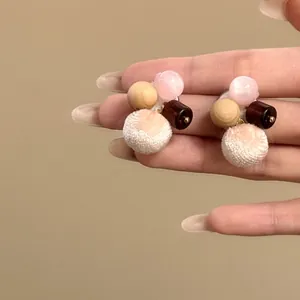 Macro detail of autumn winter wooden bead and cat eye stone earrings with soft pink pompoms