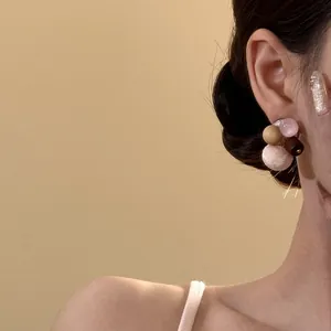 Close-up detail of a sweet pink autumn winter earring with wood and cat's eye stone beads