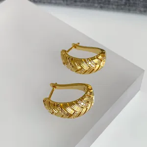 Detailansicht der 18k vergoldeten Creolen mit geometrischer Textur und Zirkonia-Steinen.