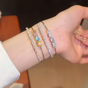 Close-up of luxury 18k gold plated open bangles and zircon bracelets worn on a wrist.