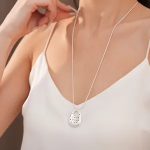 Detail view of silver oval pendant necklace with minimalist perforated dot pattern