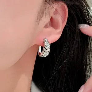 Elegante 18k vergoldete Creolen mit Zirkonia und geometrischen Mustern auf dem Ohr.