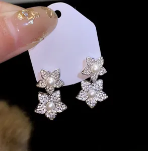 Close-up of elegant silver flower stud earrings featuring pearls and micro-paved zircons.