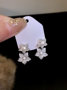 Detailed view of elegant micro-pave zircon flower stud earrings featuring central pearls