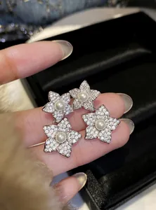 Macro view of delicate flower stud earrings featuring white pearls and micro-set zircons