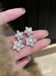 Macro detail of sparkling cubic zirconia flower stud earrings featuring central white pearls.