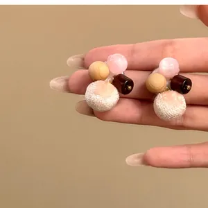 Detailed shot of autumn winter fabric wood and cat's eye stone stud earrings