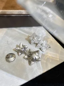 Detailed macro view of silver flower earrings with micro-inlaid zirconia and central pearls