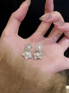 Close-up detail of elegant silver flower stud earrings with zircons and pearls held on hand