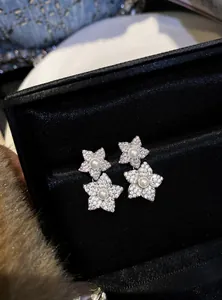 Detailed shot of sparkling flower drop earrings with central pearls in black gift box