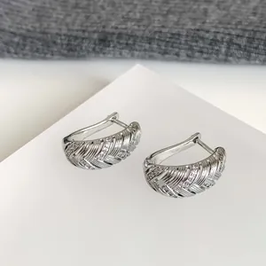 Detailansicht von 18k weißvergoldeten geometrischen Creolen mit Zirkonia-Steinen.