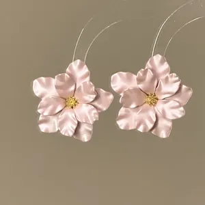 Elegante rosa Blumenohrstecker mit goldener Mitte auf klaren Kunststoff-Displayständern.