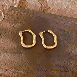 Gedetailleerde close-up van onregelmatige gouden oorringen op een houten ondergrond.