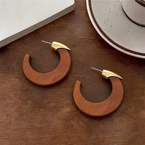 Détail de boucles d'oreilles créoles en bois vintage avec accents métalliques dorés.