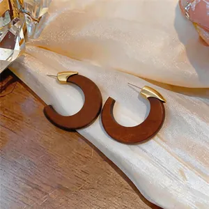 Vue détaillée de boucles d'oreilles en bois en forme de C avec finition en métal doré chic