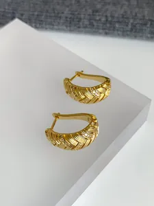 Detailansicht der 18k vergoldeten Creolen mit geometrischen Texturen und kleinen Zirkonia-Steinen.