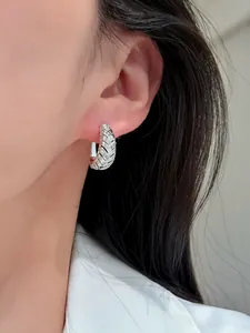 Detailansicht eines silbernen Creolen-Ohrrings mit Zirkonia am Ohr des Models