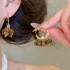 Close-up of retro 18K gold-plated earrings with brown tiger-eye resin beads detail