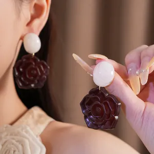 Gros plan détaillé de boucles d'oreilles élégantes en résine avec perles ovales blanches.