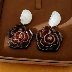 Gros plan de boucles d'oreilles roses en résine marron avec aiguilles en argent.