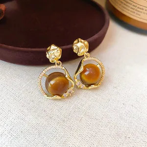 Detail of 18K gold plated earrings with brown tiger eye resin stones and crystals