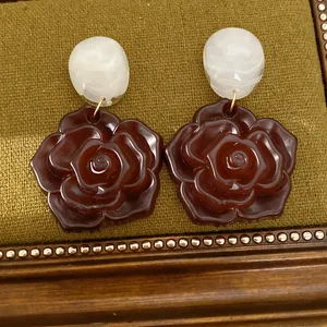Gros plan de boucles d'oreilles pendantes en résine avec roses et marbre.