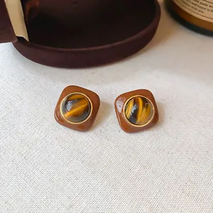 Close-up of retro Maillard style resin stud earrings with tiger eye stone center