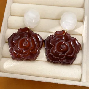 Gros plan de boucles d'oreilles en résine avec perles blanches et roses rouge foncé
