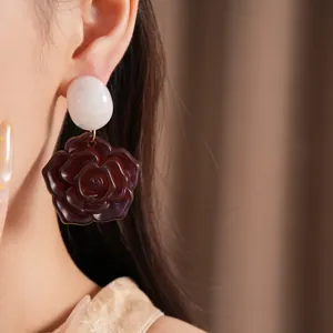 Détail de boucles d'oreilles fleurs en résine avec clou ovale blanc et rose bordeaux