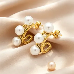 Gedetailleerd overzicht van elegante gouden C-vormige oorringen met witte parels.