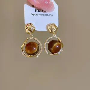 Macro view of 18K gold plated hoop earrings with polished brown tiger eye resin stones