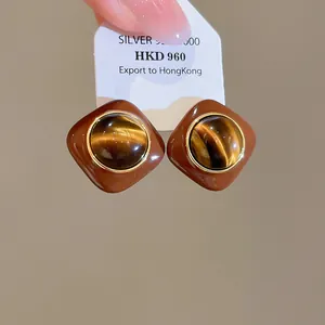 Close-up of vintage brown resin stud earrings with tiger eye stone centers