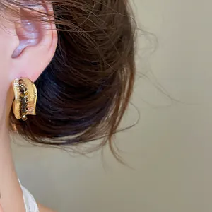 Close-up of 18K gold-plated vintage earrings with brown tiger eye resin beads.