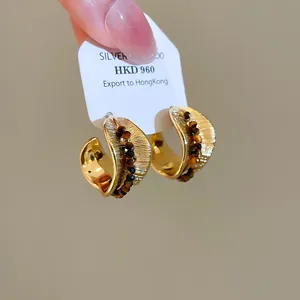 Macro view of 18K gold plated earrings featuring tiger eye stone beads and wave design