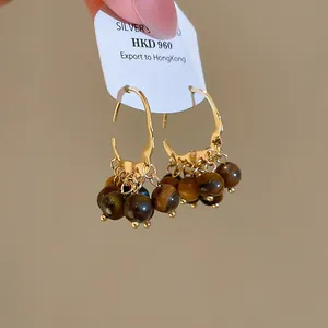 Detail view of 18K gold plated hoop earrings with brown tiger eye resin beads.