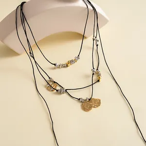 Dettaglio collana a più strati in cordino nero con ciondoli a petalo in oro e argento