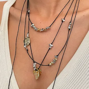 Dettaglio di una collana a più strati in cordoncino di cuoio con ciondoli oro e argento